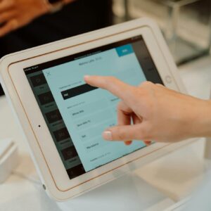 Close-up of a hand interacting with a tablet at a checkout counter, illustrating modern retail technology.