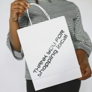 Close-up of a woman holding a shopping bag with a thank you message supporting local business.