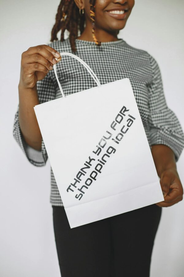 Close-up of a woman holding a shopping bag with a thank you message supporting local business.