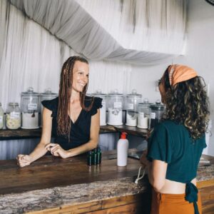 Smiling shopkeeper and customer at eco-friendly zero waste store counter.